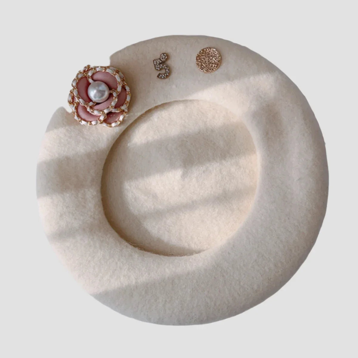 Cream-colored beret with floral and rhinestone embellishments.