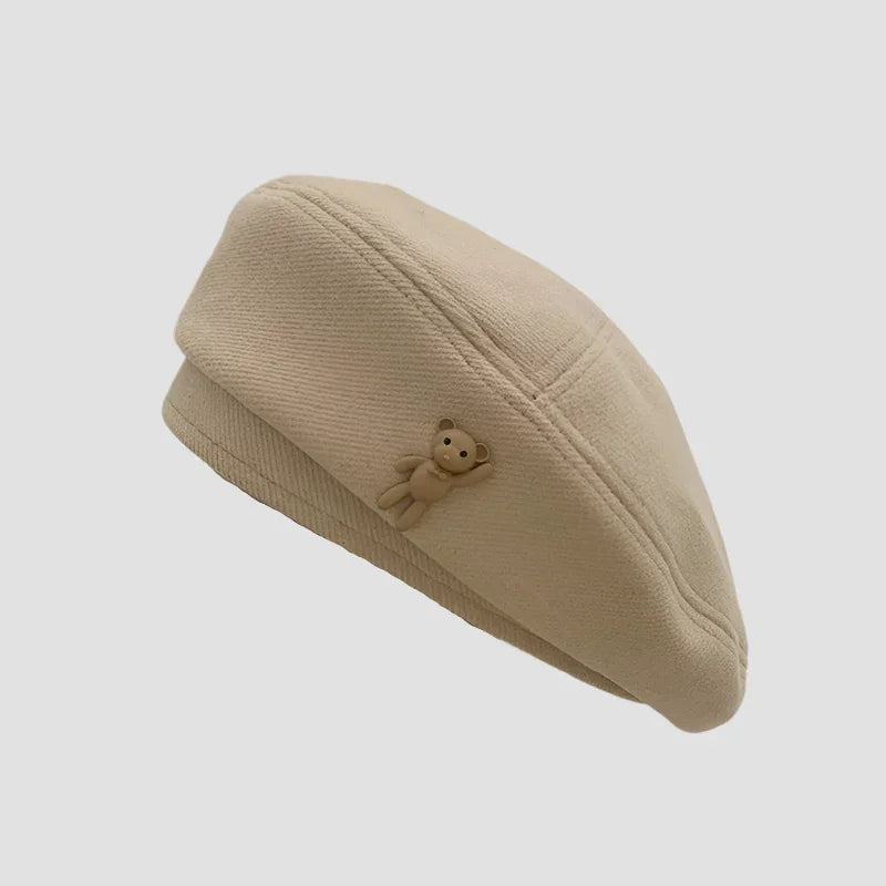 Beige beret with teddy bear accent.