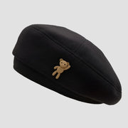 Black beret with teddy bear accent.