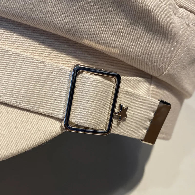 Beige hat with metal buckle.