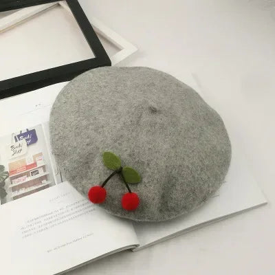 Gray beret with cherry embellishment.