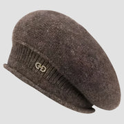 Brown knitted beret with a decorative emblem.