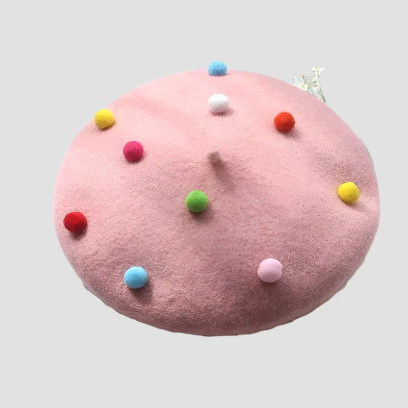 Pink beret with colorful pom-poms.