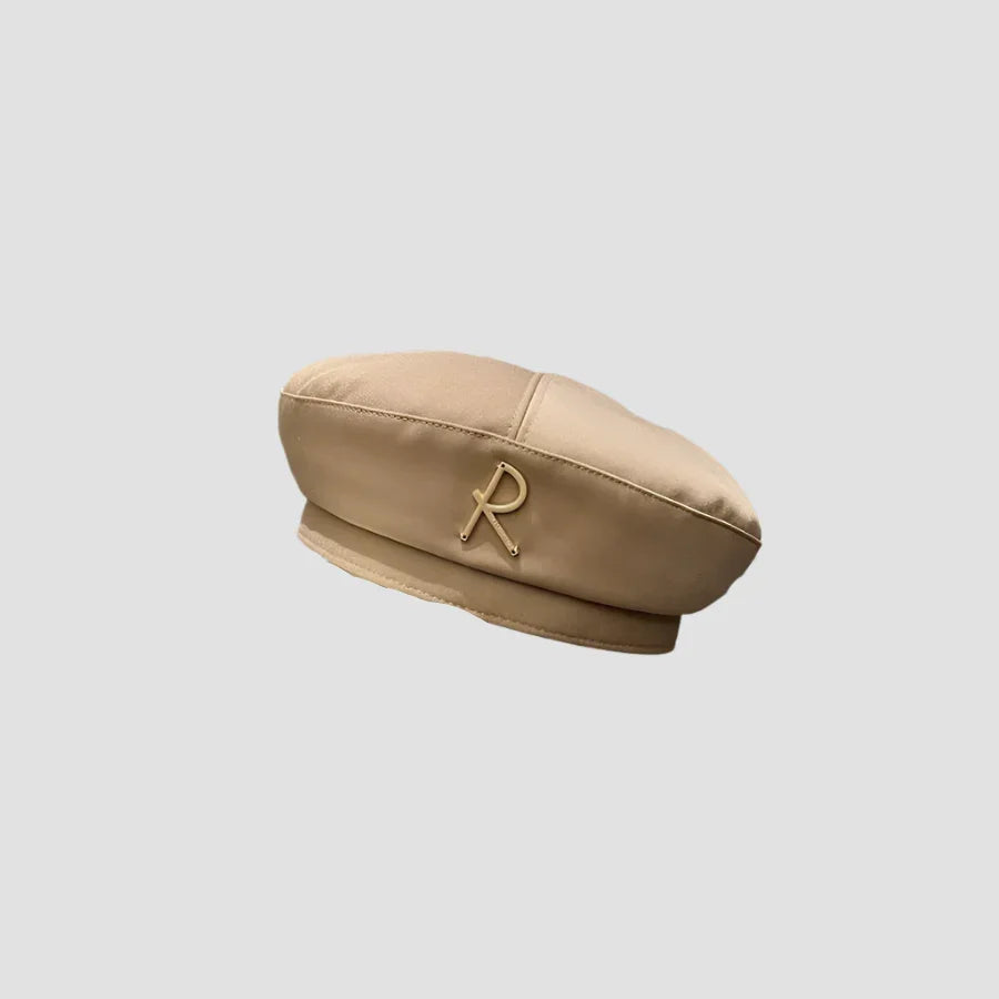 Beige beret with a gold ’R’ emblem.