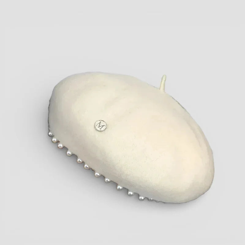 Cream-colored beret with silver emblem and pearl beaded trim