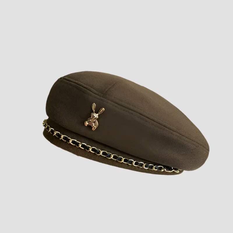 Olive-green beret with gold chain and rabbit pin.