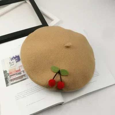 Tan beret with cherry embellishments.