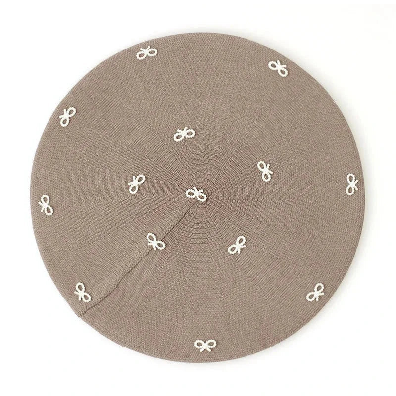 Beige circular placemat with embroidered white bow motifs for Crochet Beret with Bow