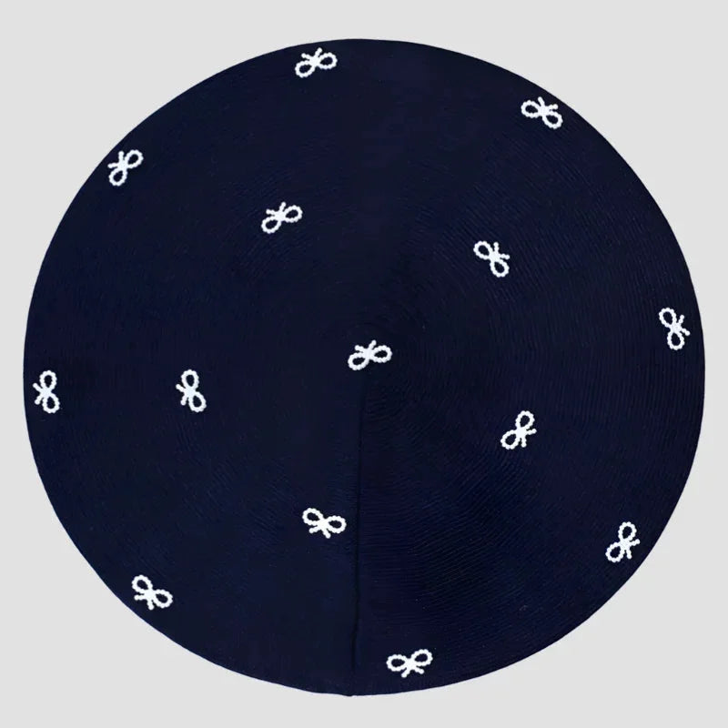 Dark blue circular kippah with white embroidered bow patterns