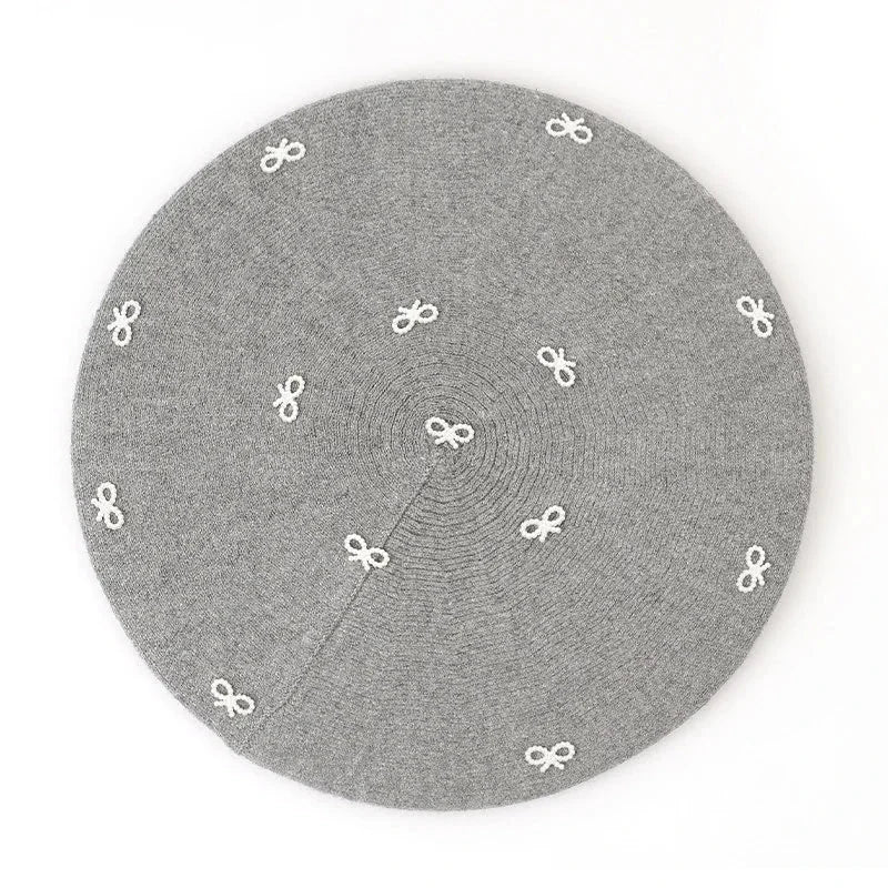 Gray circular crochet beret rug with white bow motifs
