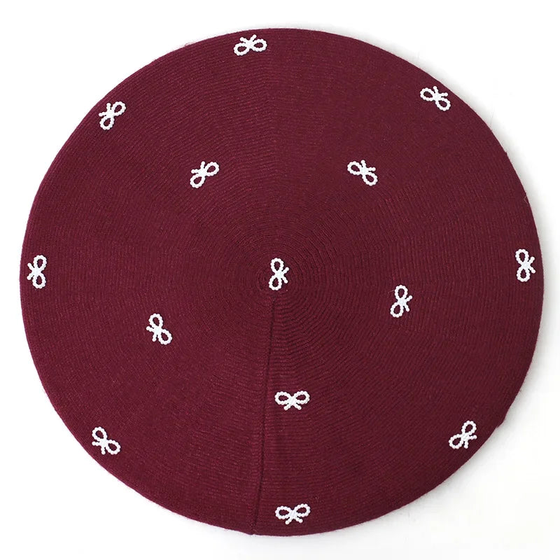 Maroon knit kippah with white bow accents.