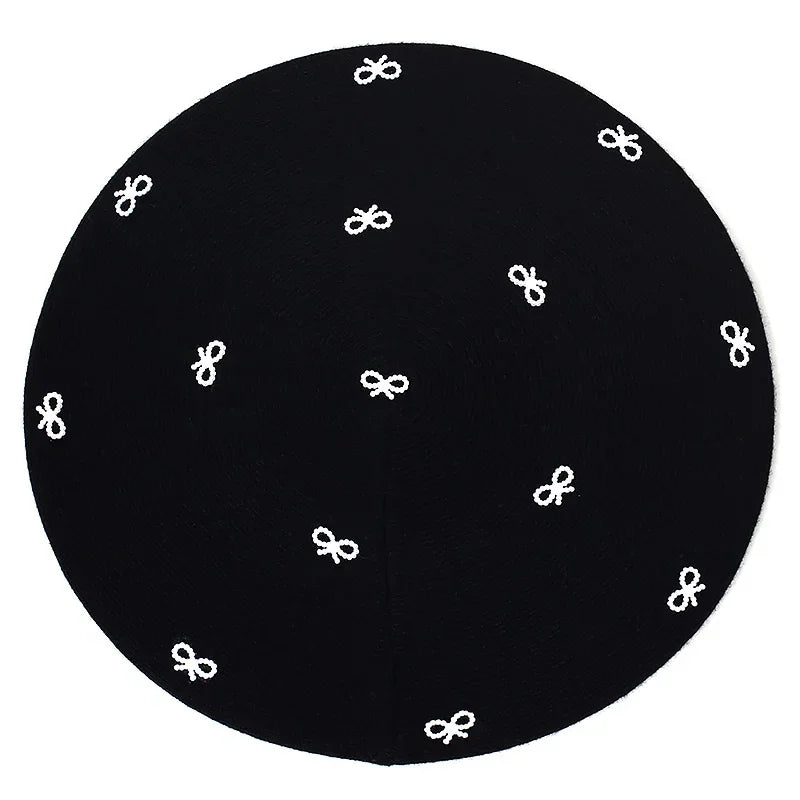 Round black rug with white bow pattern.