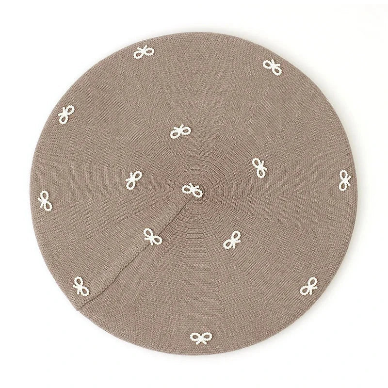 Taupe beret with bow accents.