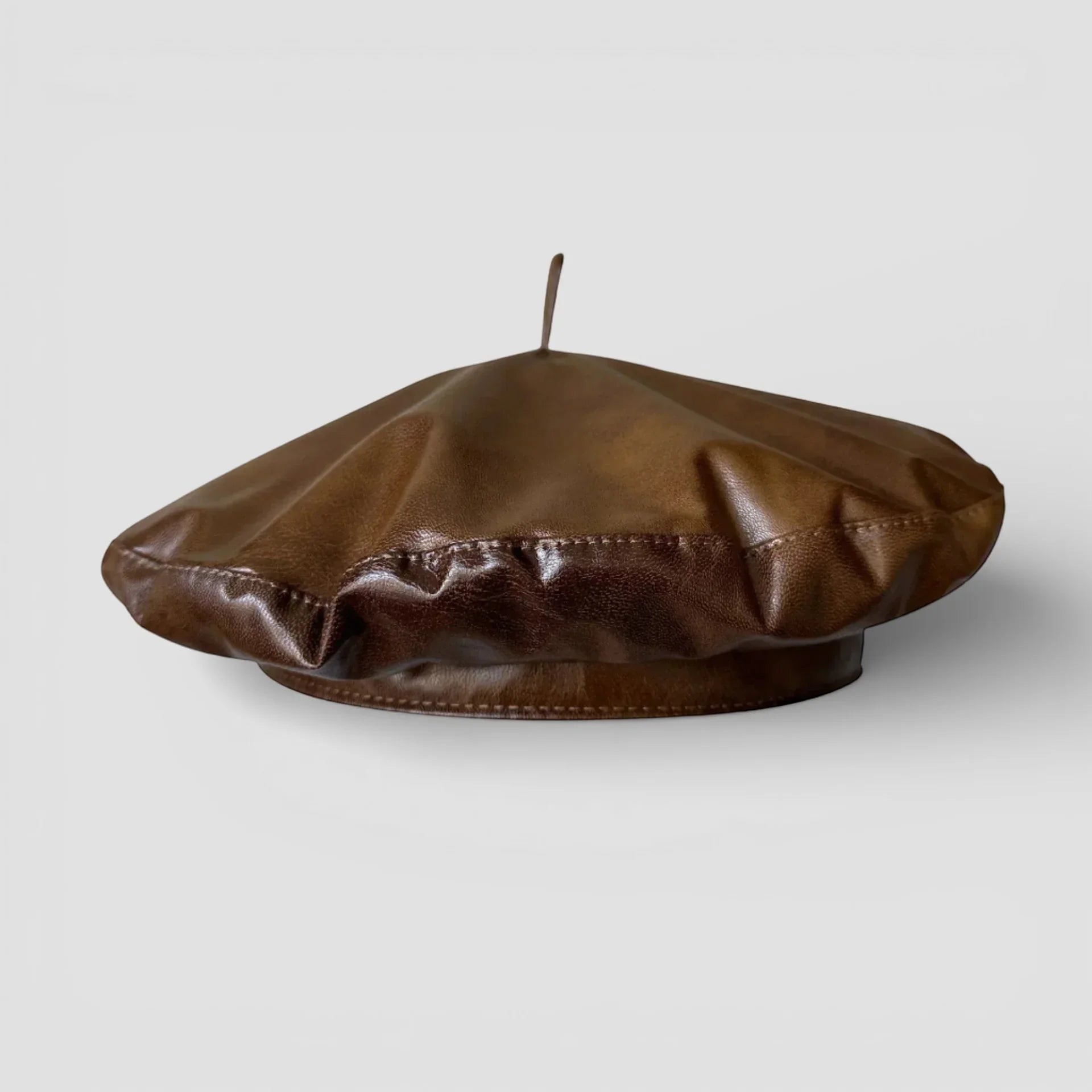 Dark orange leather beret with soft wrinkled texture and central button