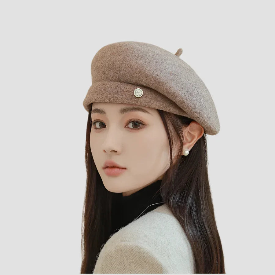 Beige beret with button detail.