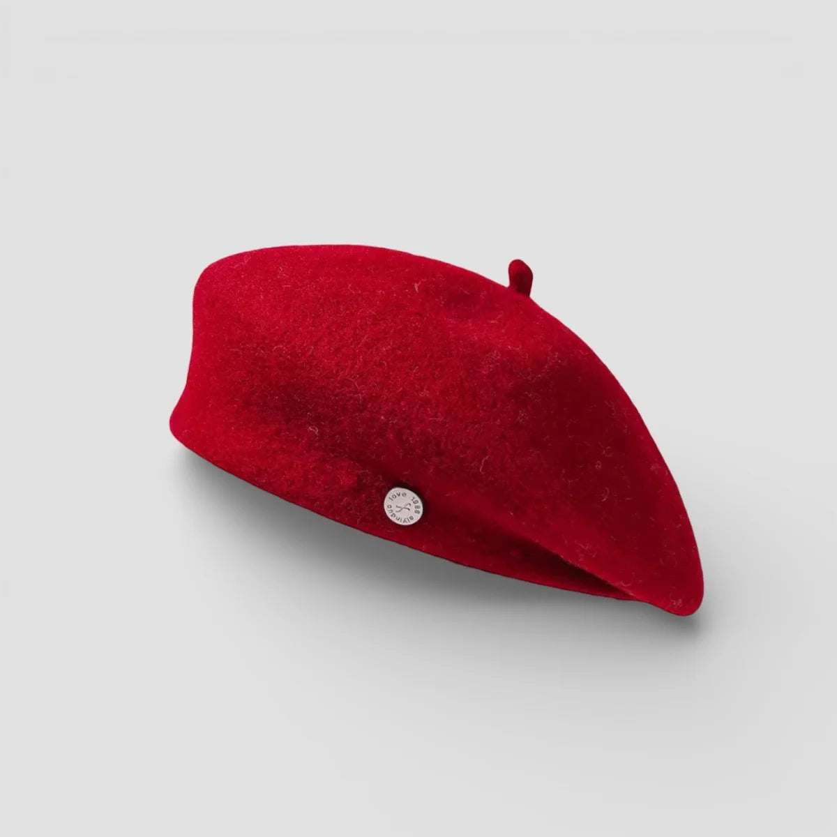 Vibrant red felted wool beret with small silver emblem on side