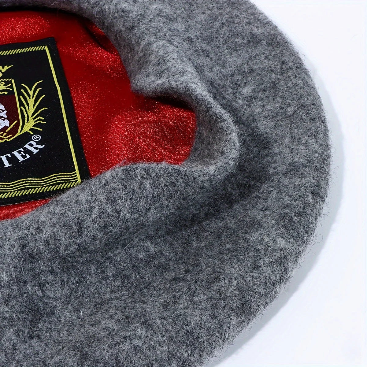 Gray felt hat with a red interior and a brand label on a white background