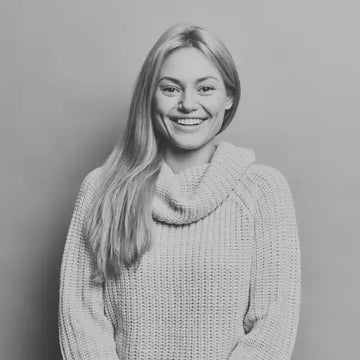 Black and white photo of a person wearing a knitted sweater against a plain background beret