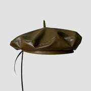Olive green leather beret with black ties.