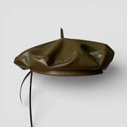 Green leather beret with olive green faux leather, central button, black strap