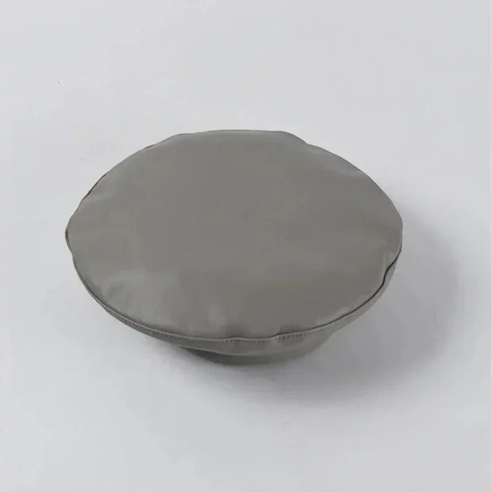 Gray circular cushion with soft padded texture and stitched edges on Grey Leather Beret