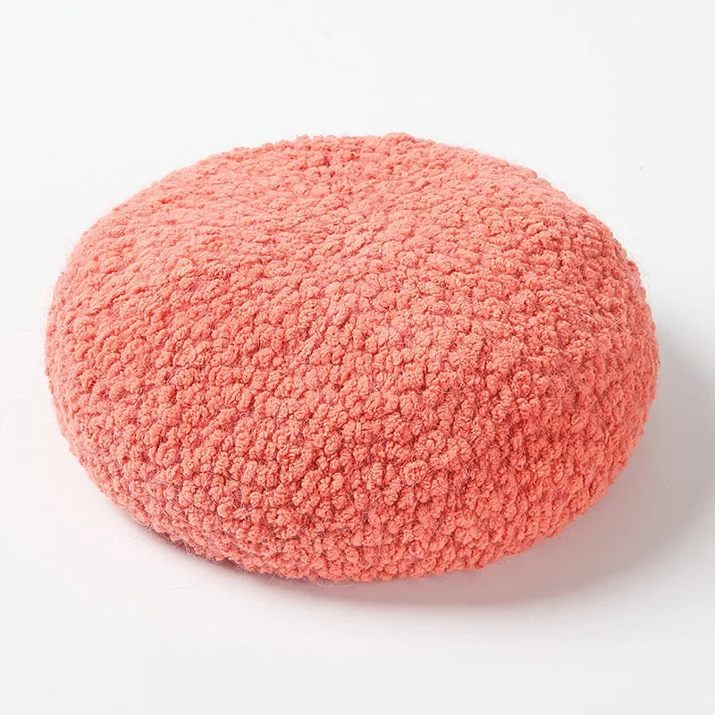 Round, coral-colored, textured cushion.
