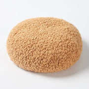 Round, tan, sherpa-textured cushion.