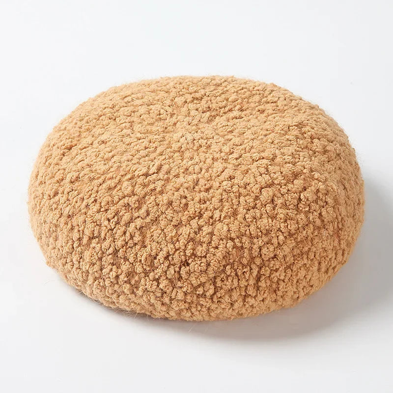 Round, tan, sherpa-textured cushion.