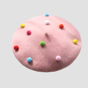 Pink beret with colorful pom-poms.