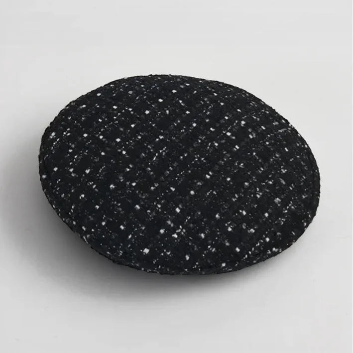 Traditional Basque Beret black circular cushion with textured woven fabric and white specks