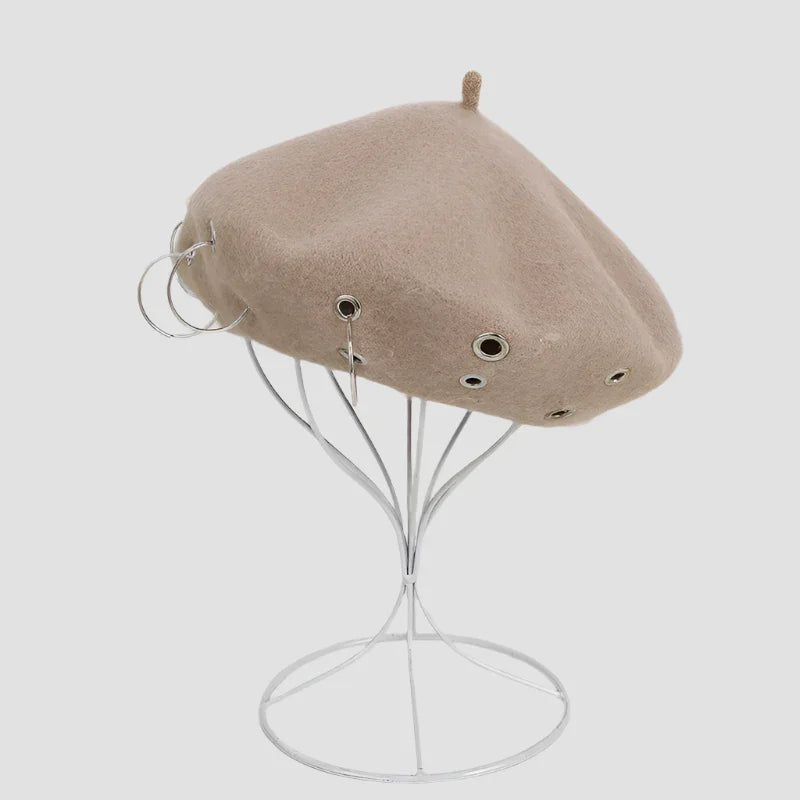 Beige beret with metal eyelets and rings.