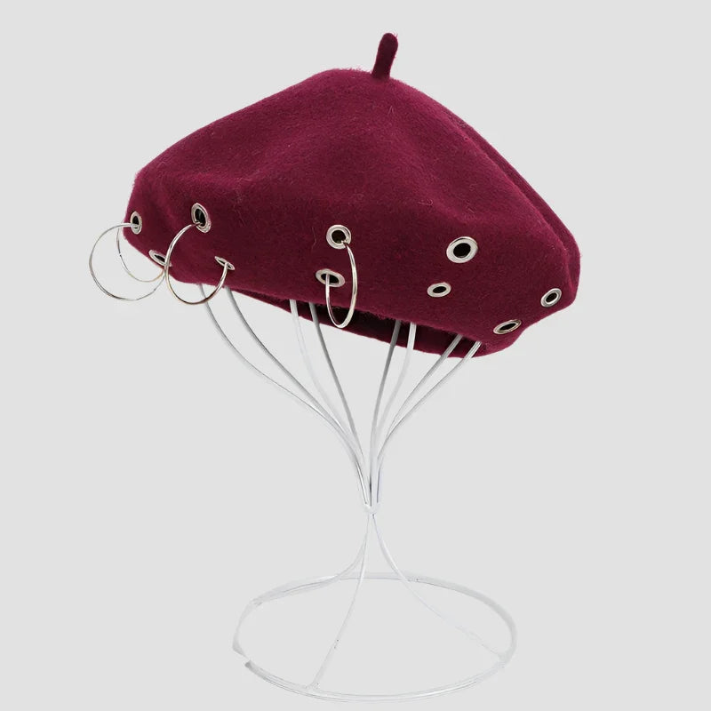 Maroon beret with silver grommets and hoop earrings.